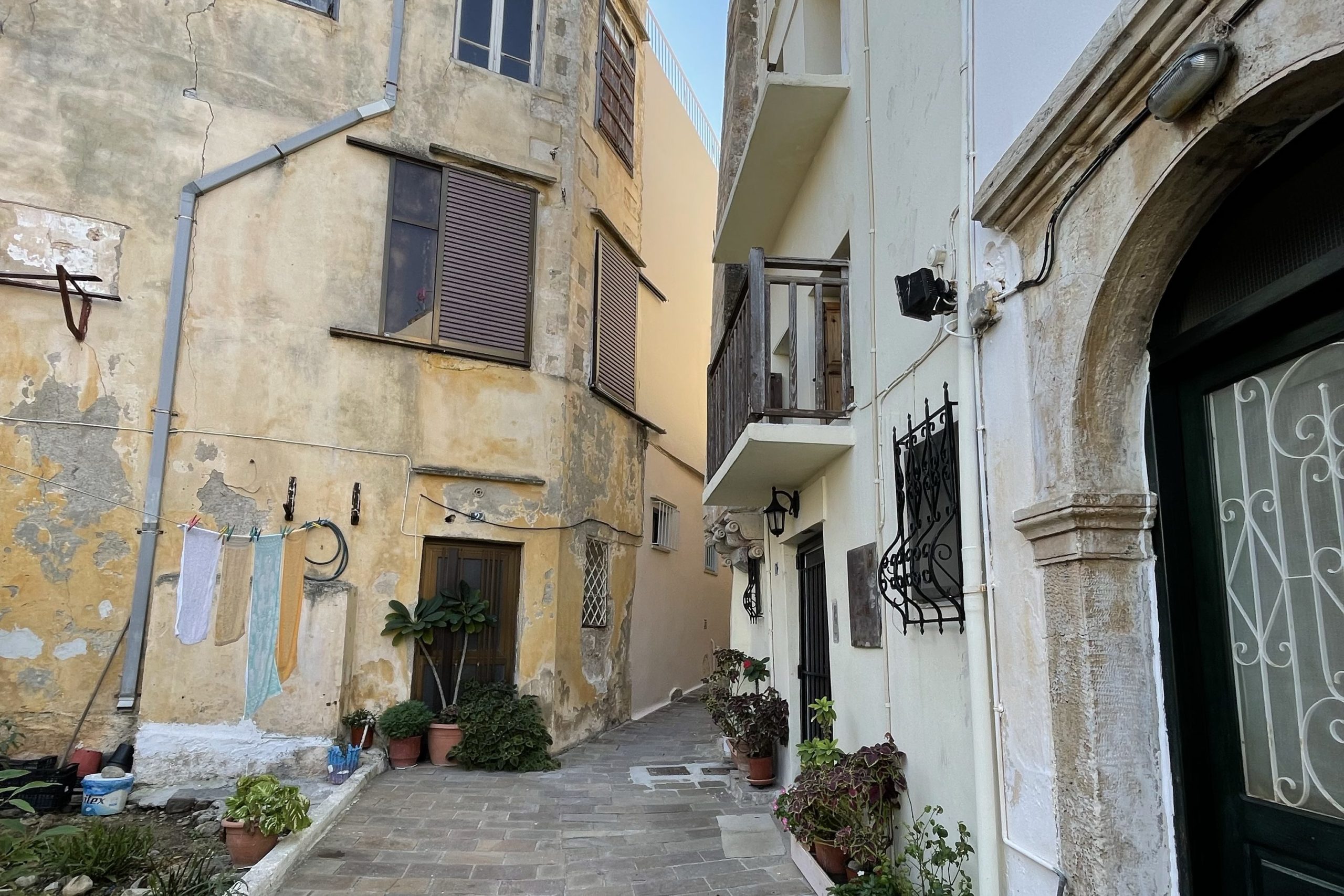 A small street in Crete with the white stone facade of the Ashtanga Yoga Crete studio